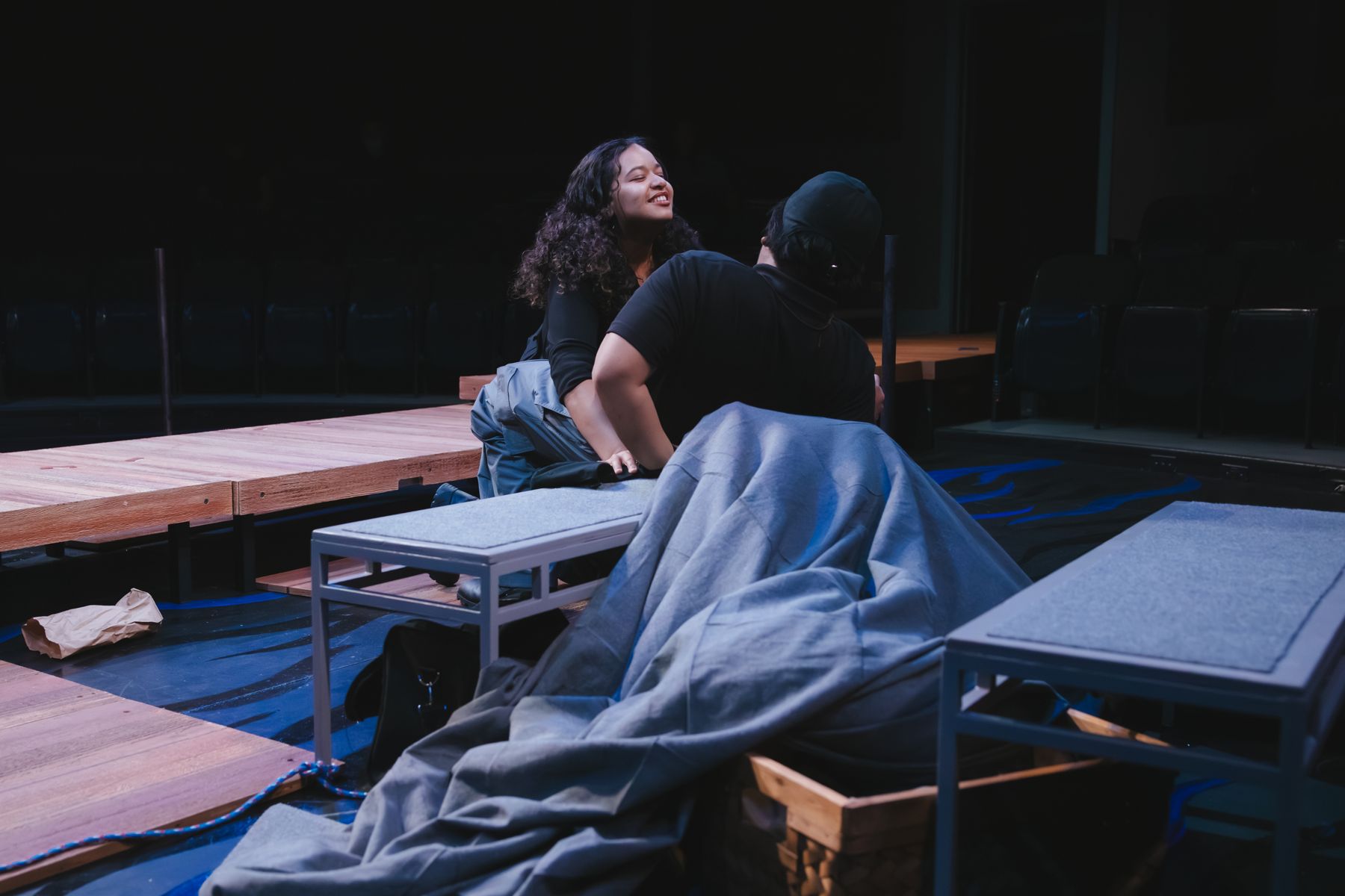 Two performers on a blanket-strewn set