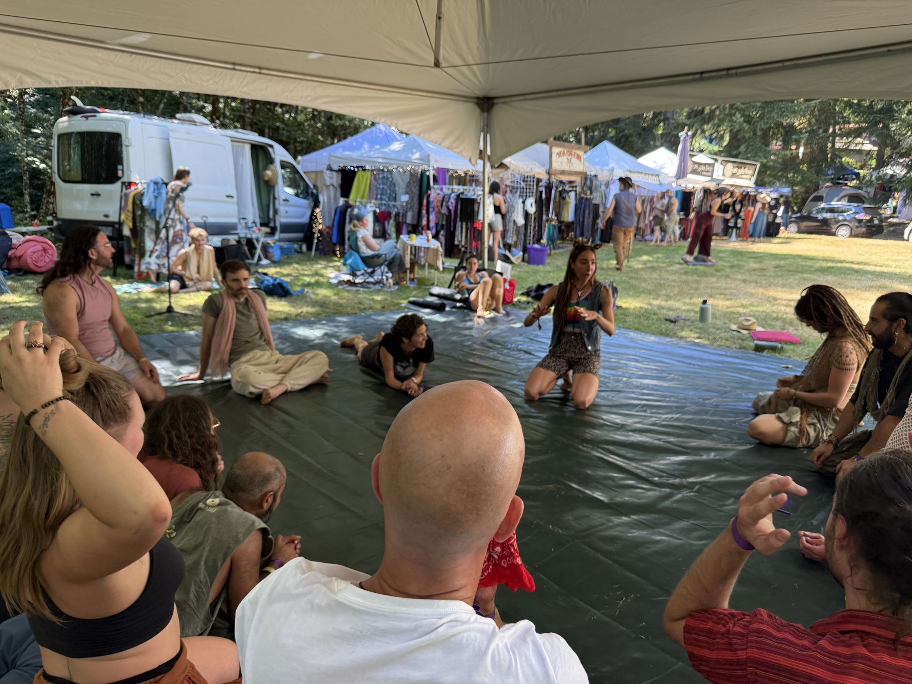 Workshop participants seated in a circle under a tent
